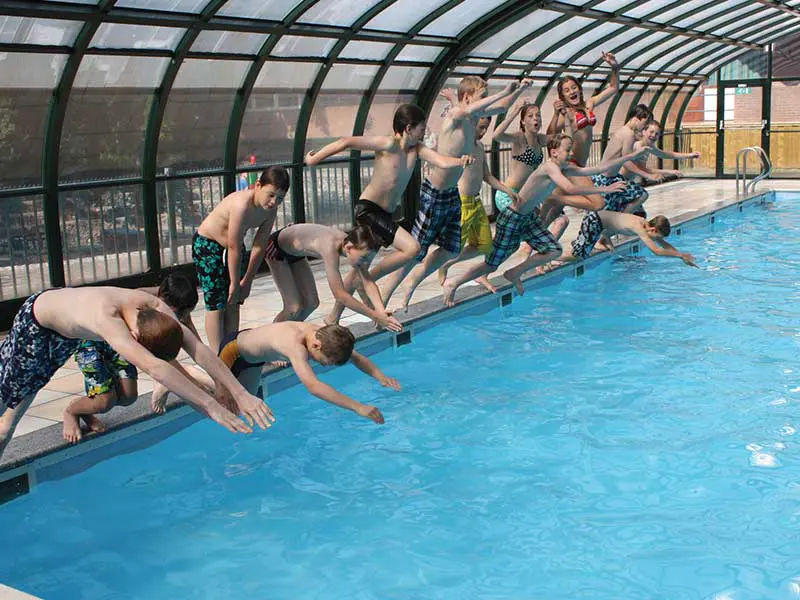 Groep die het zwembad in springt